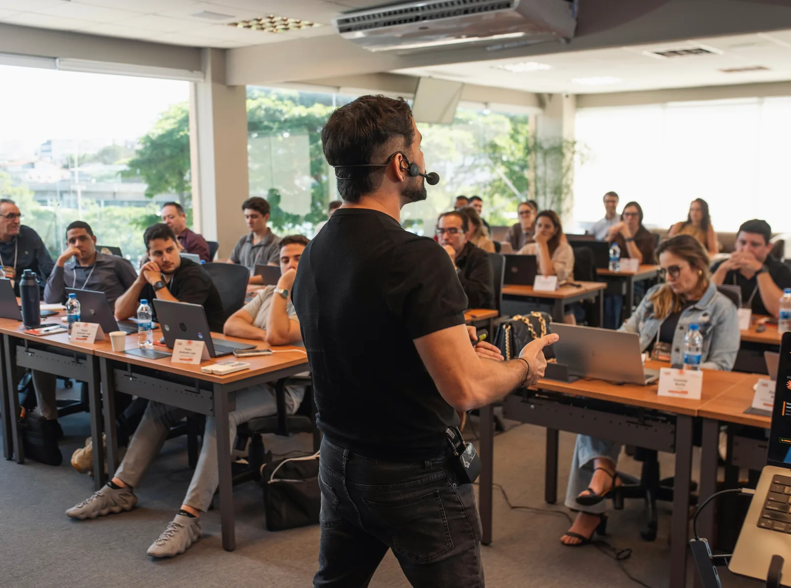 Breno conduzindo uma turma do Claude for Business em Vitória, com a sala cheia e os participantes de notebook aberto